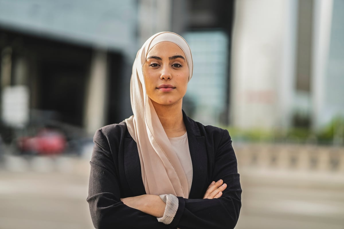 Portrait of Arab business woman in hijab and suit with arms crossed looking at camera